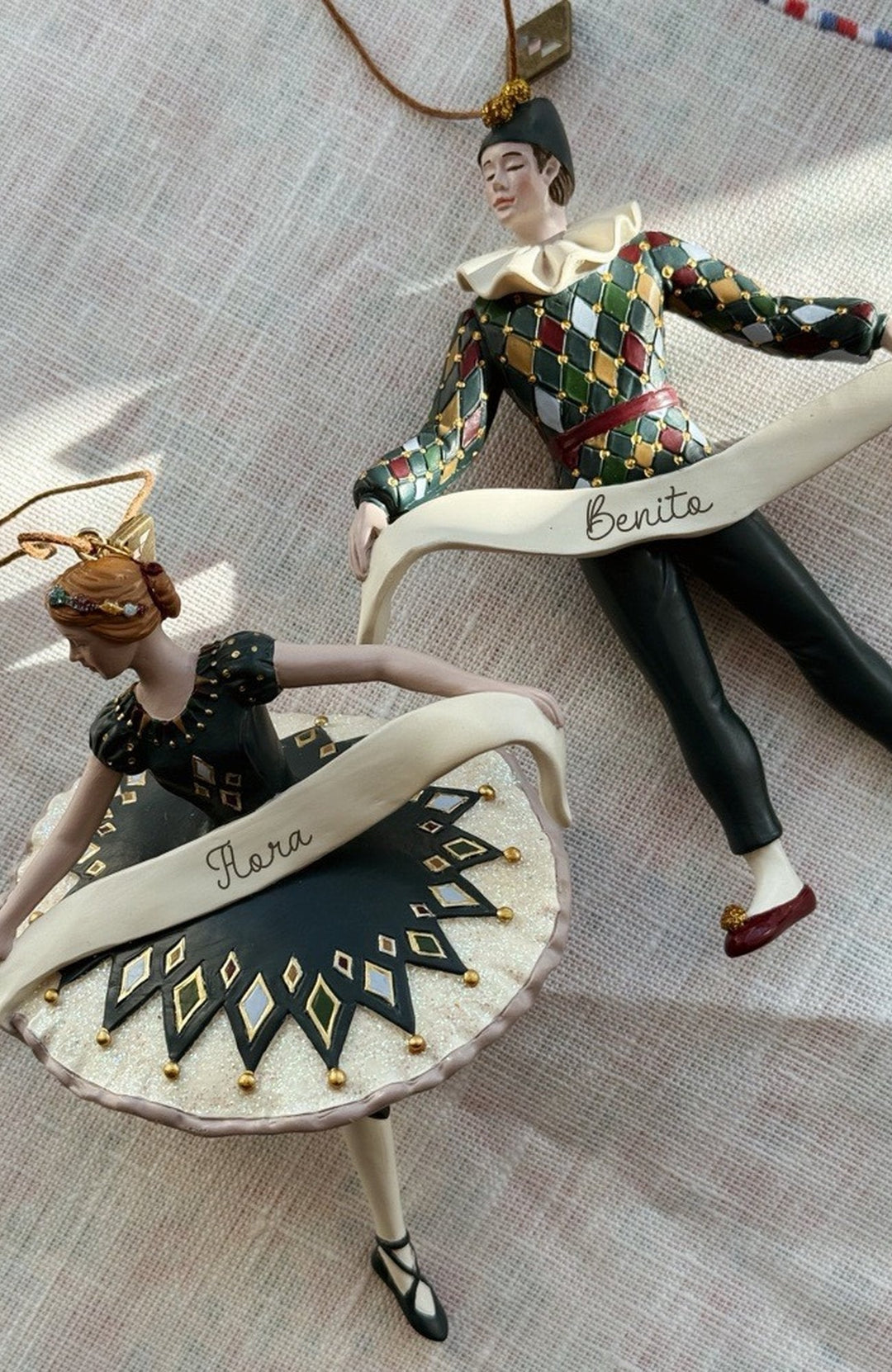 Julpynten Harlekin och Ballerina liggande på en linneduk