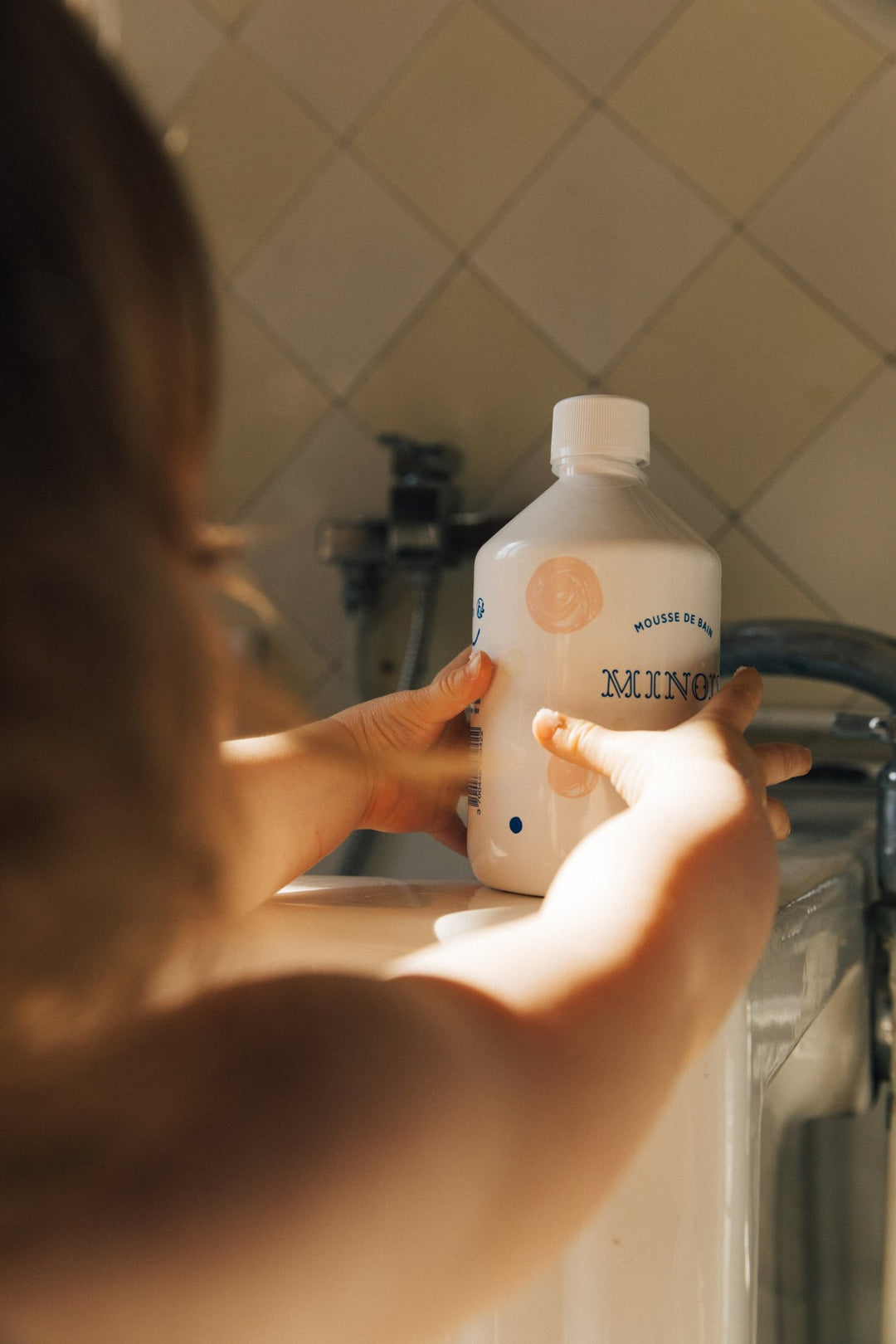 Barn som sträcker sig efter Bubble Bath på badkarskanten