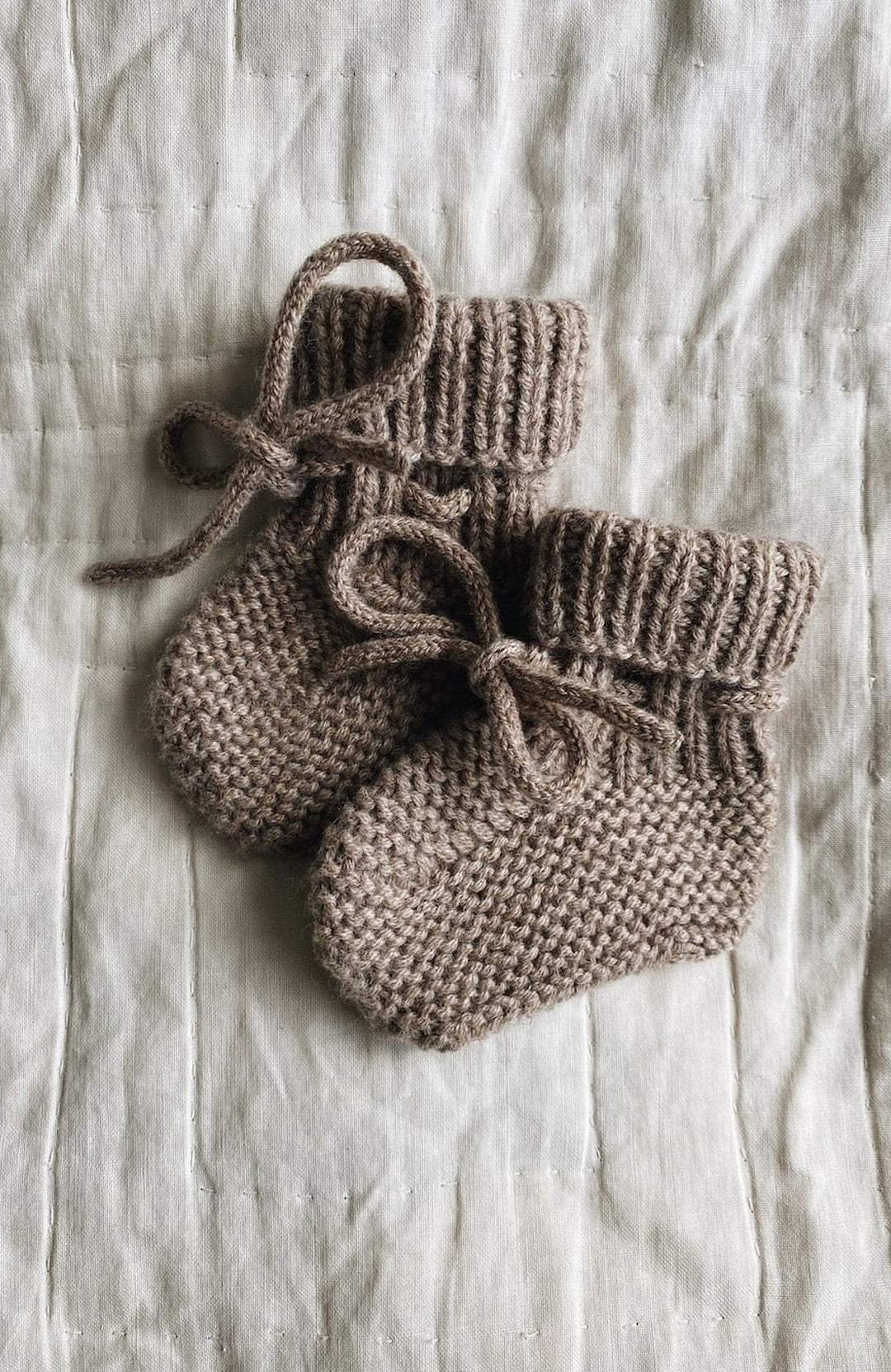 Alpha Shoes i Toast från Lalaby – stickade babytossor i ljusbrunt med knytband